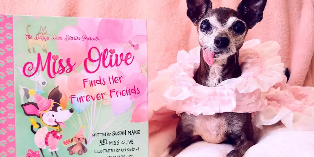 Miss Olive with a copy of Miss Olive Finds Her “Furever” Friends, written by Susan Marie and Miss Olive.