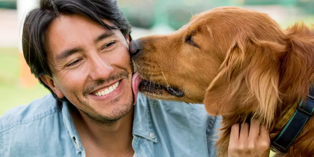 A picture of a pet parent who taught his dog to give kisses on the cheek. 