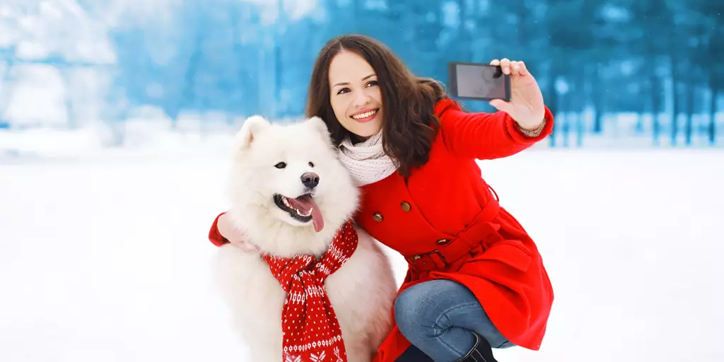 A woman taking a selfie with her dog during the holidays.